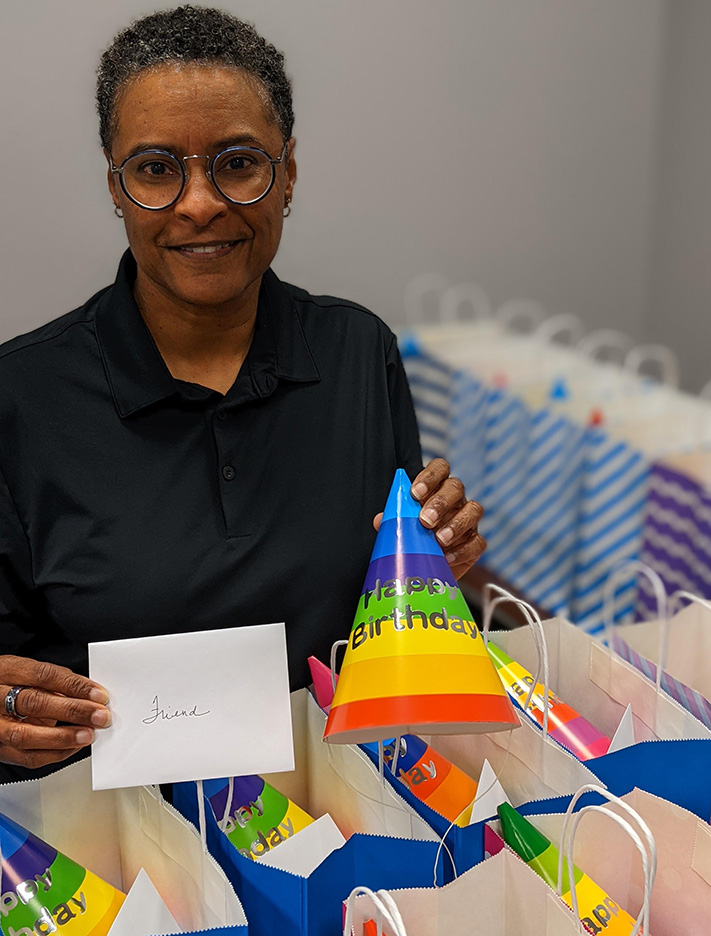 African American woman engineer volunteers. Holding birthday present she assembled.